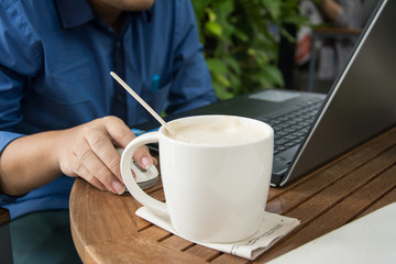 man with a cup of coffee working on his laptop