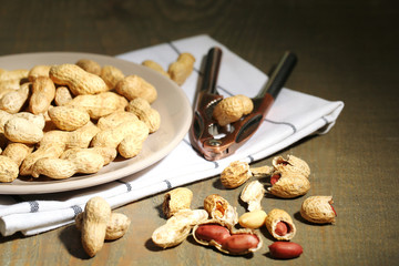 Peanuts on plate, on wooden background