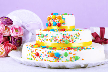Beautiful tasty birthday cake and gifts on color background