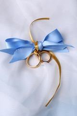 Wedding rings tied with ribbon on light background