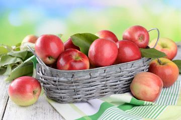 Fototapeta na wymiar Sweet apples in wicker basket on table on bright background