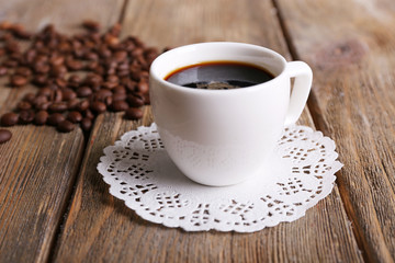 Obraz na płótnie Canvas Cup of coffee and coffee beans on napkin on wooden background