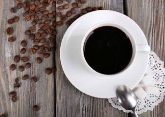 Cup of coffee and coffee beans on napkin on wooden background