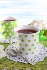 Two cups and sugar on napkin on table on light background
