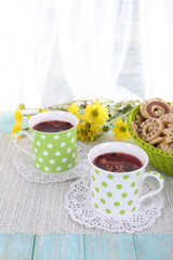 Two polka dot cups of tea with biscuits