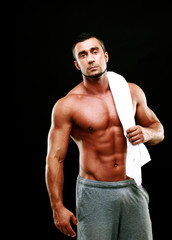 Fototapeta premium Handsome muscular man holding towel on black background