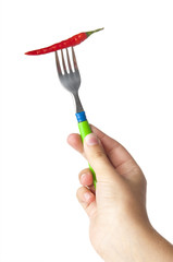 Red hot chili pepper impaled on steel fork in hand