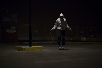 Hooded athlete skipping at night under a street light - 70340178