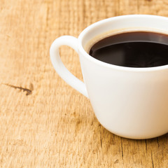 Black coffee in white ceramic cup on wooden table - 1 to 1 ratio