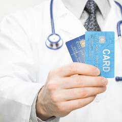 Doctor holding two credit cards in his hand - 1 to 1 ratio