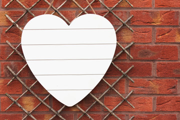 White wooden heart on brick wall. Copy Space