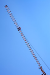 Modern tower crane against blue sky. Arrow of the tower crane.
