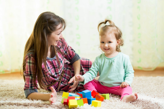 happy mom and kid play toys at home