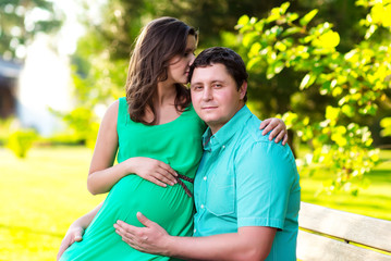 Obraz premium Happy and young pregnant couple hugging in nature