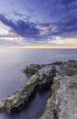 Grand majestic rocks on the shore silky ocean at sunset