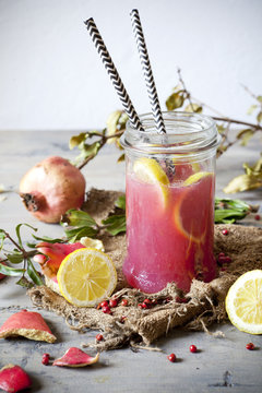 pomegranate and lemon smoothie on glass jar with two straw