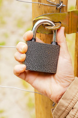 Robotnik zamyka bramę na kłódke kluczem © Mirek