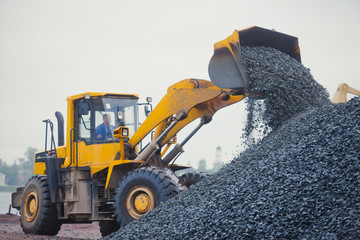 Yellow heavy excavator and bulldozer unloading road metal during © tsuguliev