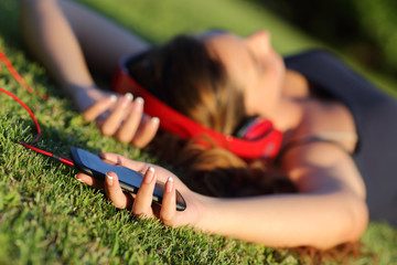 Girl listening music with headphones and holding a smart phone