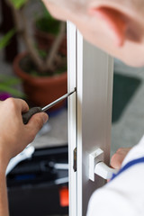 Obraz premium Handyman repairing window with screwdriver