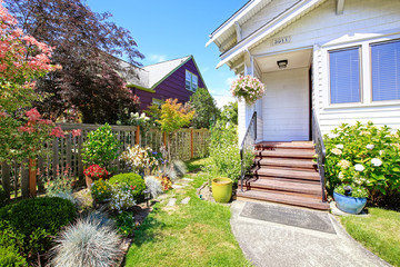 Simple house exterior. Entrance porch with stairs and flower bed