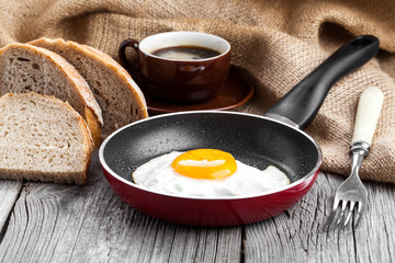 Fried egg in a frying pan, on an old wooden table