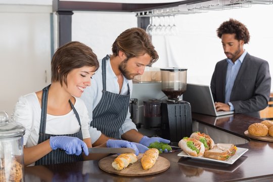 Happy servers preparing sandwiches together