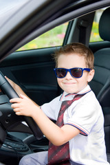 Boy with glasses and tie sitting in car