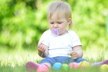 Cute baby playing on grass in garden.