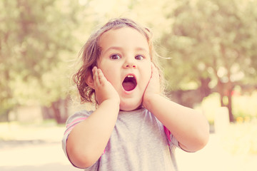 outdoor portrait of surprised cute child girl on natural backgro