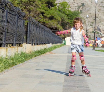cute happy child girl roller skating on natural background