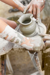 child learning how to make a pot on a potery wheel, old potter h