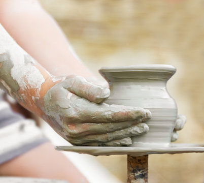 child learning how to make a pot on a potery wheel, old potter h
