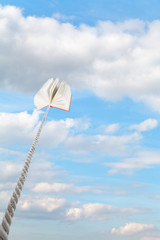 book tied on cord soars into light blue sky