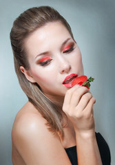 Studio portrait of young woman with strawberry