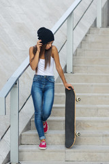 Teenager with skateboard full body portrait on the stairs.