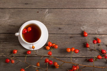 cup of tea with hip roses, on wooden table