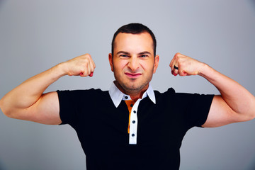 Man in casual cloth showing his biceps on gray background