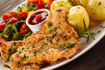 Fried pork chop, boiled potatoes and vegetable salad