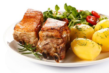 Tasty grilled ribs with vegetables on white background