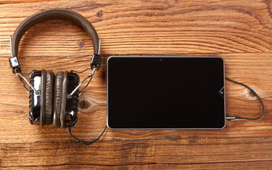 Tablet with headphones on old wooden desk.