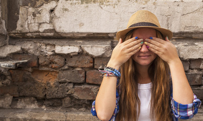 Hipster girl on a street closes his eyes with his hands.