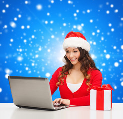 smiling woman with gift box and laptop