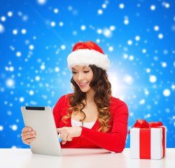 smiling woman in santa hat with gift and tablet pc