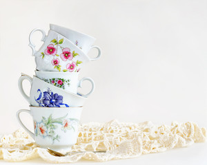 Stack of vintage tea cups on white