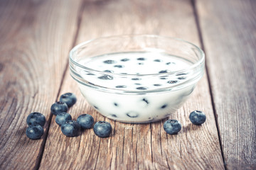 Fresh blueberries with milk in bowl on wooden table 