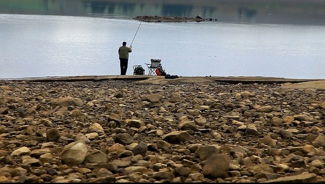 man fishing at reservoir uk