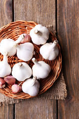 Fresh garlic on wicker mat, on wooden background
