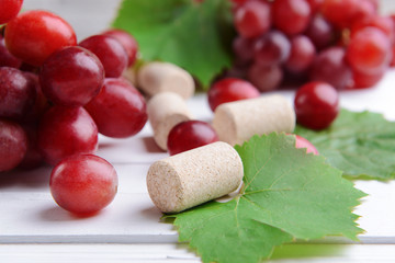 Wine bottle corks with grapes on table close-up