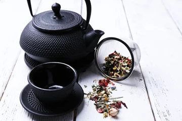 Foto op Aluminium Black teapot, bowl and tea on color wooden background © Africa Studio